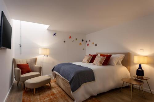 a bedroom with a large bed and a chair at STUPENDO- Two Rooms, patio With refreshing Pond-Center-Air conditioning in Lisbon