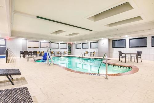 a pool in a building with tables and chairs at Holiday Inn Express & Suites Longview North, an IHG Hotel in Longview