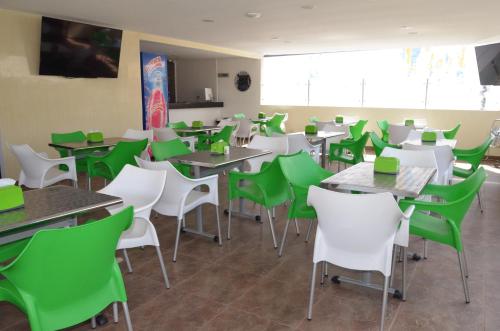 a dining room with green and white tables and chairs at La Pera Hotel in Bucaramanga