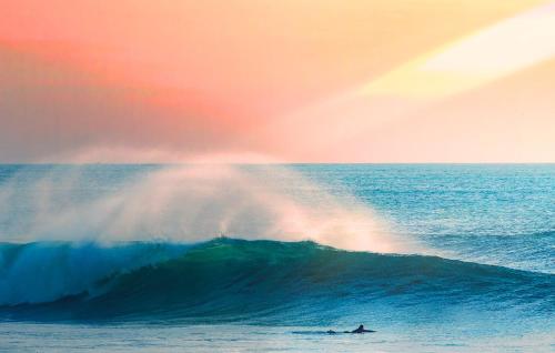 a surfer riding a wave in the ocean with a rainbow at Maria Tereza Sea Villa in Costa da Caparica