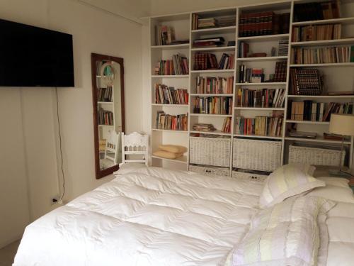 Una cama blanca en una habitación con estanterías. en La biblioteca en Olavarría