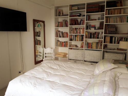 a white bed in a room with book shelves at La biblioteca in Olavarría