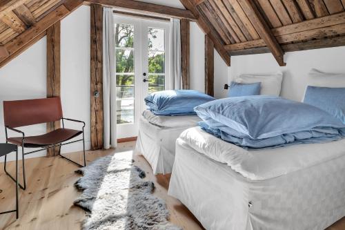 twee bedden in een kamer met een stoel en een raam bij Boen Gård in Kristiansand