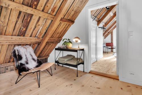 a room with wooden ceilings and a chair and a table at Boen Gård in Kristiansand