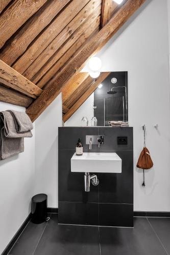 a bathroom with a white sink and wooden ceilings at Boen Gård in Kristiansand