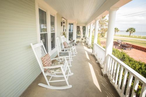a porch with white rocking chairs on a house at The Peaceful Pelican LLC in Palacios