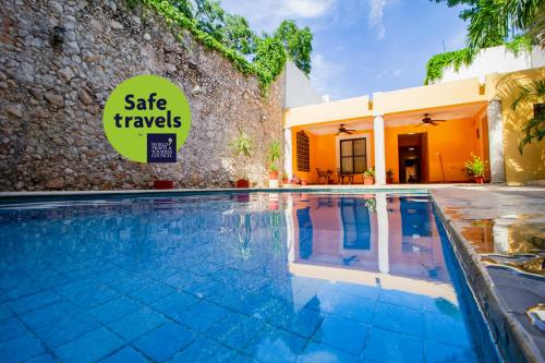 a swimming pool in front of a house with a sign that reads safe travels at Hotel Montejo in M&eacute;rida