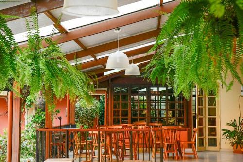 Un comedor con mesas y sillas y plantas. en Pousada Solmaior, en Conservatória