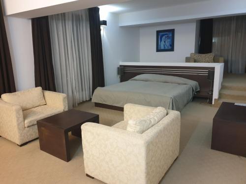 ロヴェチにあるHotel Presidivm Palaceのベッド1台と椅子2脚が備わるホテルルームです。