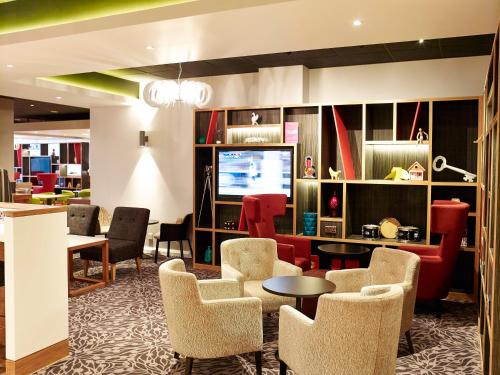 a lobby with chairs and tables and a television at Holiday Inn Liverpool City Centre by IHG in Liverpool