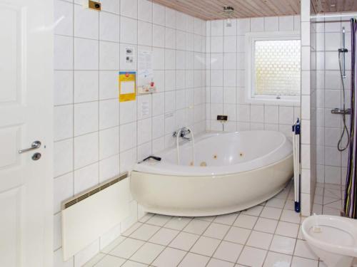 a white bathroom with a tub and a toilet at 8 person holiday home in Hemmet in Falen