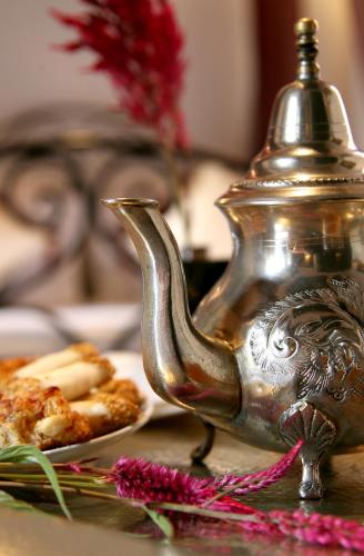 a silver tea kettle on a table with a plate of food at Riad Terra Bahia in Marrakech