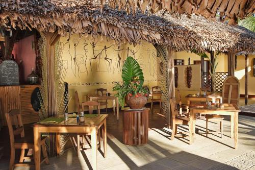 a restaurant with tables and chairs and a plant at Sambatra Bed and Breakfast in Ambaro