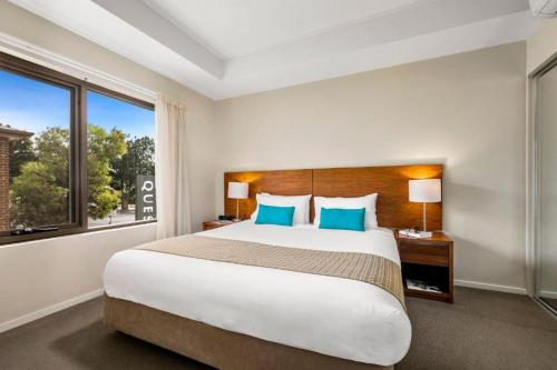 - une chambre avec un grand lit et une grande fenêtre dans l'établissement Quest Bendigo Central, à Bendigo