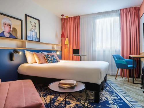 pokój hotelowy z dużym łóżkiem i stołem w obiekcie Ibis Styles Paris Gennevilliers w mieście Gennevilliers