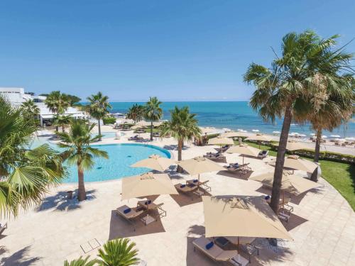 an aerial view of a resort with a pool and palm trees at Mövenpick Hotel Gammarth Tunis in Gammarth