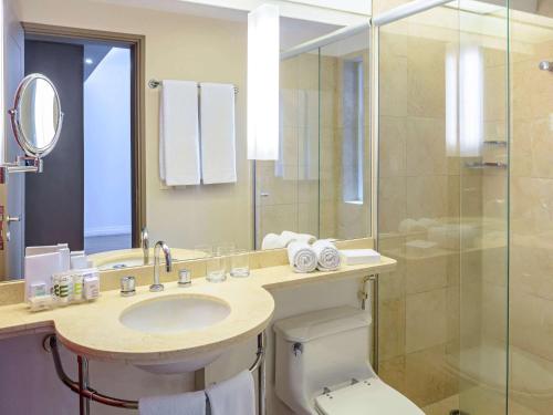 een badkamer met een toilet, een wastafel en een douche bij Mercure Sao Paulo Jardins in Sao Paulo
