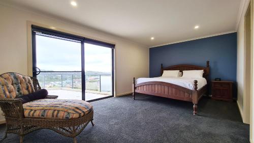 a bedroom with a bed and a chair and a window at A Vista in Forster
