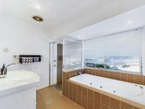 een badkamer met een bad en een wastafel bij Seaward Werri Beach Gerringong in Gerringong