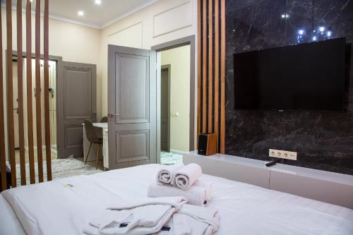 a bedroom with a bed with towels and a flat screen tv at Апартаменты #120 VIP в ЖК Заман in Atyrau