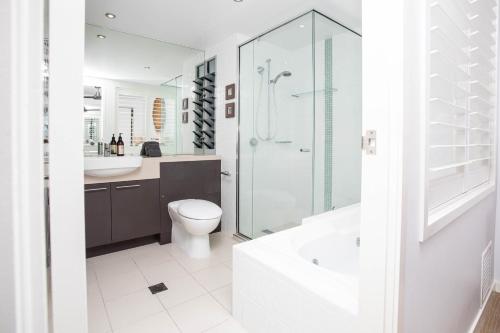 a bathroom with a toilet and a shower and a sink at By The Sea Shore With Pool in Airlie Beach