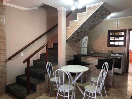 a dining room with a table and chairs and a staircase at Pé na areia gaivotas com Wi-Fi in Itanhaém