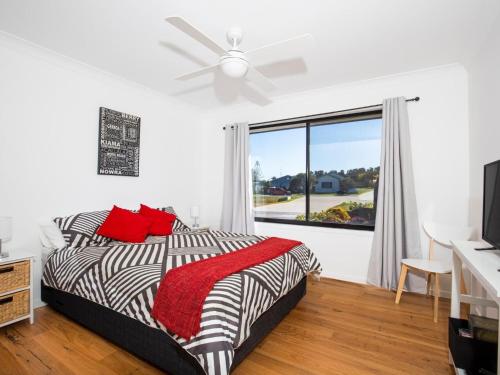 una camera da letto con un letto con cuscini rossi e una finestra di Villa Zelma I Pet Friendly I 4 Min Walk to Beach a Culburra Beach