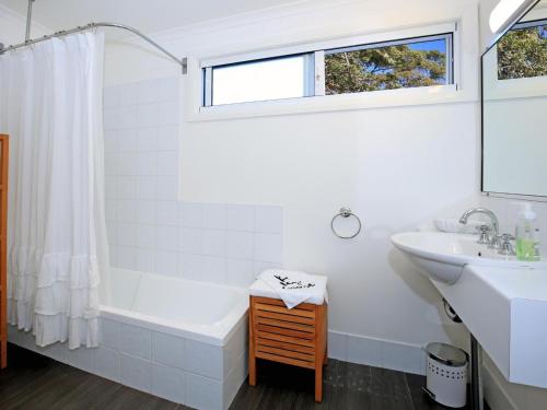 Baño blanco con bañera y lavamanos en Jervis Bay Beach Shack I Pet Friendly, en Vincentia