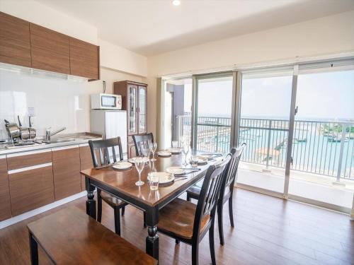 a dining room with a table with chairs and a kitchen at Seaside Condominium Rana Chatan in Chatan