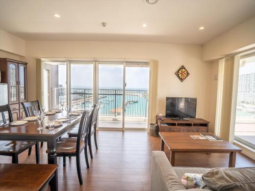a dining room with a table and a view of the ocean at Seaside Condominium Rana Chatan in Chatan
