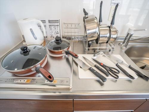 a kitchen counter with pots and pans and utensils at Seaside Condominium Rana Chatan in Chatan