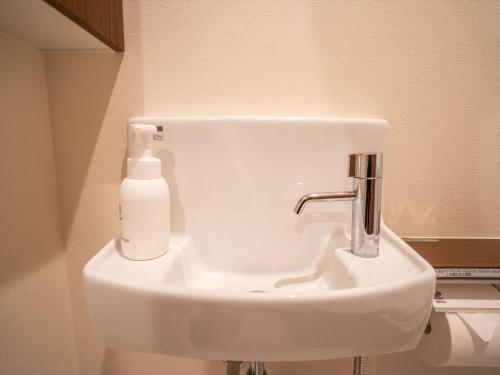 a white sink in a bathroom with a soap dispenser at Seaside Condominium Rana Chatan in Chatan