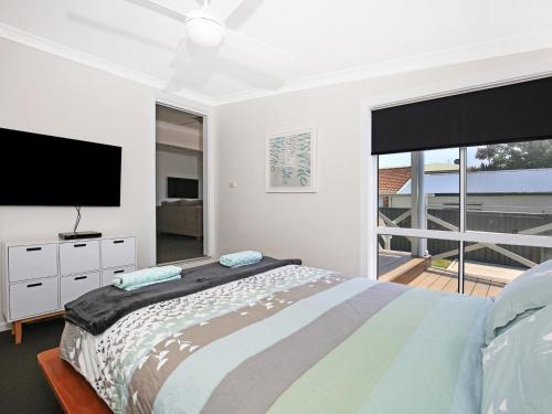 Schlafzimmer mit einem Bett und einem Flachbild-TV in der Unterkunft Tillys Retreat I Pet Friendly I 3 Min Walk to Beach in Culburra Beach