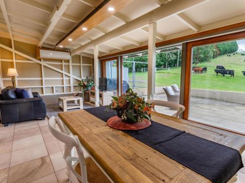 a dining room with a wooden table and a couch at The Dairy at Cavan I Kangaroo Valley I Stunning Views in Barrengarry