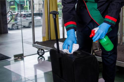 a person in blue gloves holding a piece of luggage at Eurotel Vivaldi Araneta in Manila