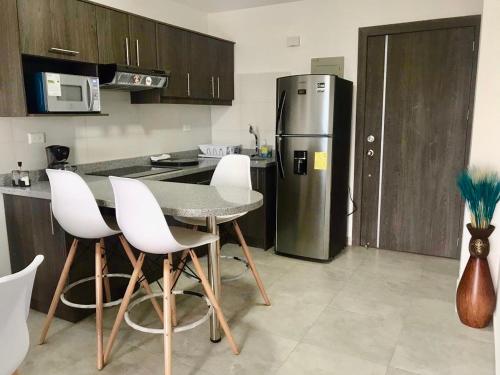 a kitchen with a table and a stainless steel refrigerator at DEPARTAMENTO TOTALMENTE NUEVO, AMOBLADO Y DE LUJO EN TONSUPA in Tonsupa