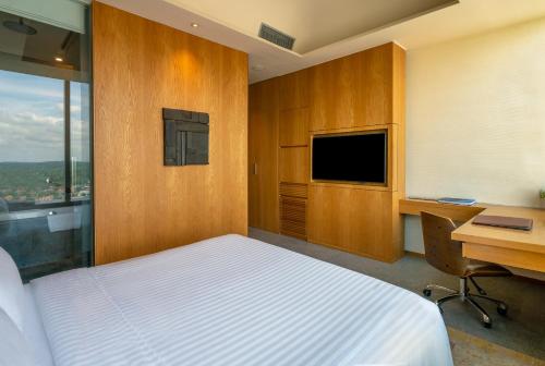 a bedroom with a bed and a desk and a television at Oasia Hotel Novena, Singapore by Far East Hospitality in Singapore