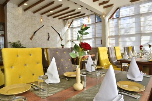 uma sala de jantar com uma mesa com uma rosa em Hotel Snowcrests Manor em Manali