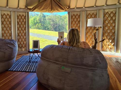 a woman sitting in a room looking out a window at Noosa Eco Retreat in Pomona