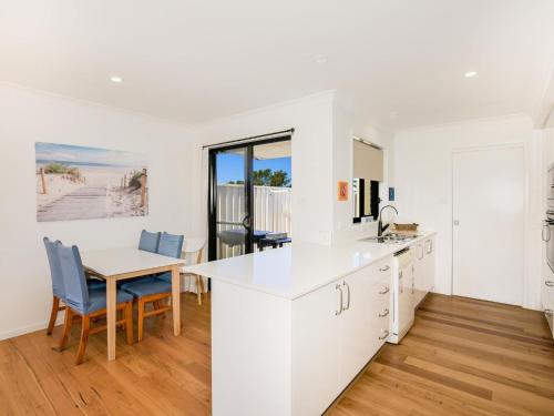 a kitchen with white cabinets and a table and chairs at Villa Zelma I Pet Friendly I 4 Min Walk to Beach in Culburra Beach