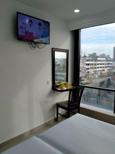 a room with a tv and a chair and a window at Grand Bagan Hotel in Butterworth