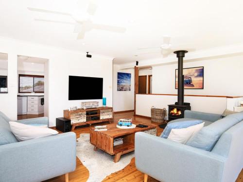 a living room with two blue couches and a fireplace at Shores I Pet Friendly I 1 Min Walk to Beach in Culburra Beach