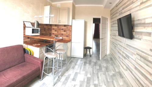 een woonkamer met een bank en een keuken met een koelkast bij Апартаменты в центре OrenRoom56 in Orenburg