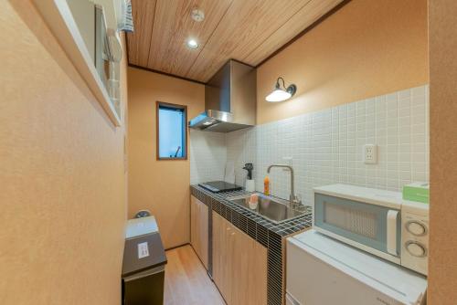 a small kitchen with a sink and a microwave at YADOYA Hakuteian in Tokyo