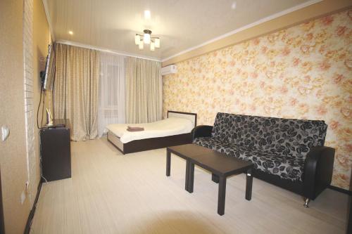 a room with a bed and a couch and a table at Апартаменты на пр Победы OrenRoom in Orenburg