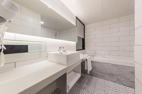 a white bathroom with a sink and a tub at Pyeongtaek Stay Tourist Hotel in Pyeongtaek