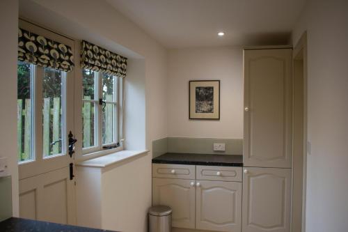 een keuken met witte kasten en een raam bij Ford End Cottage in York