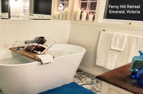 ein Badezimmer mit einer Badewanne und einer Zeitschrift darauf in der Unterkunft Ferny Hill Retreat, Emerald Victoria in Emerald