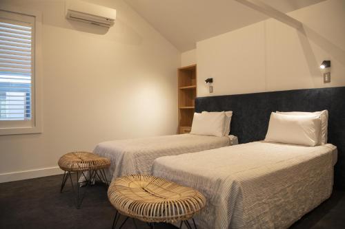 a bedroom with two beds and two stools at Loft at Shed 5 - Ahuriri Holiday Apartment in Napier