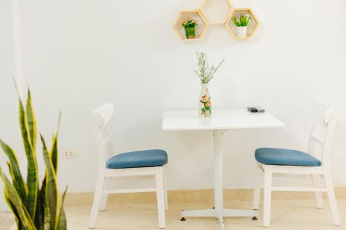 a white table with two chairs and a table with a plant at Sunstay Paradise in Hanoi